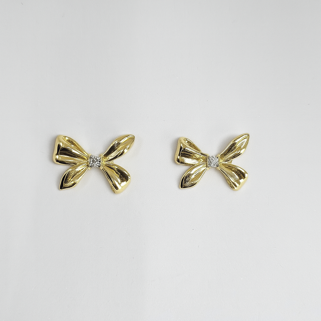 Gold bow-shaped earrings on a light gray background