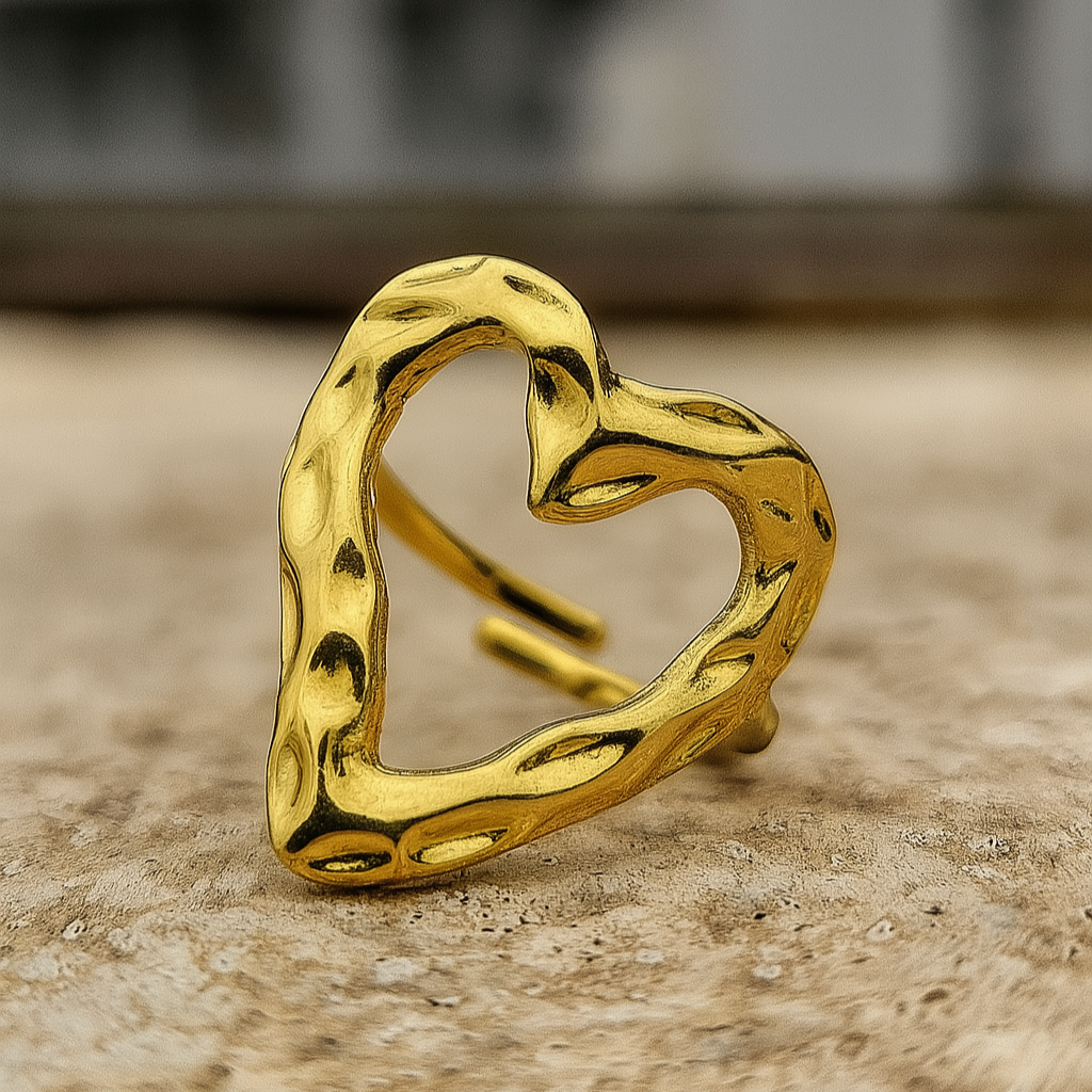Gold heart-shaped ring on a textured surface with a blurred background