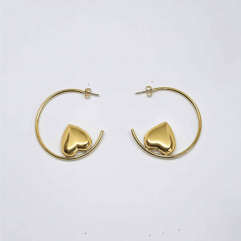 Gold hoop earrings with heart-shaped ends on a white background