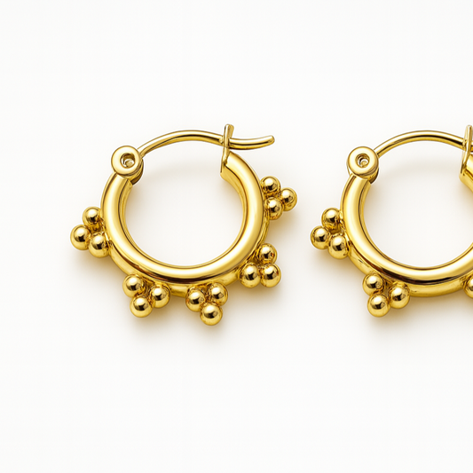 Pair of gold hoop earrings with small spherical embellishments on a white background