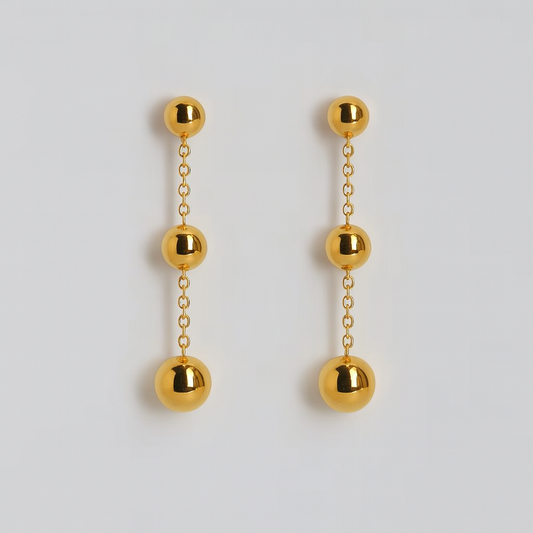Gold ball drop earrings on a light gray background

