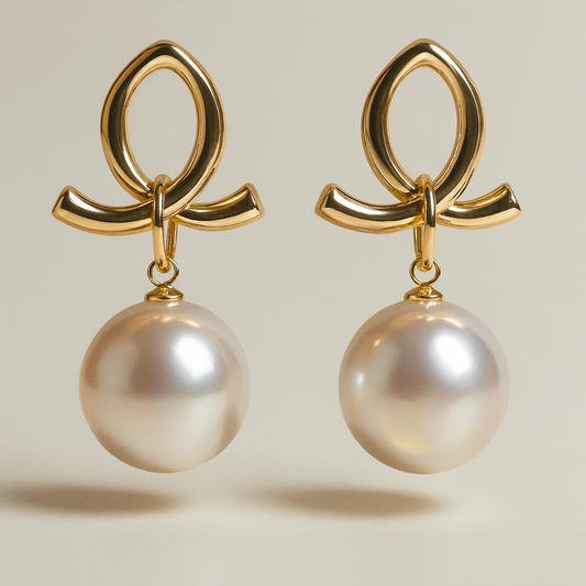 Gold earrings with pearl drops on a beige background

