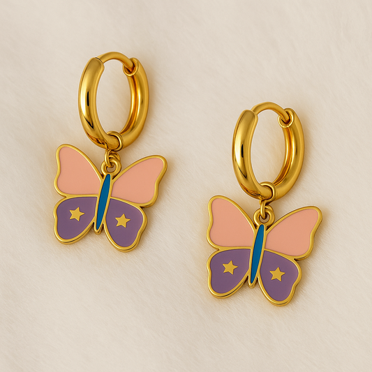 Gold hoop earrings with butterfly charms on a beige background

