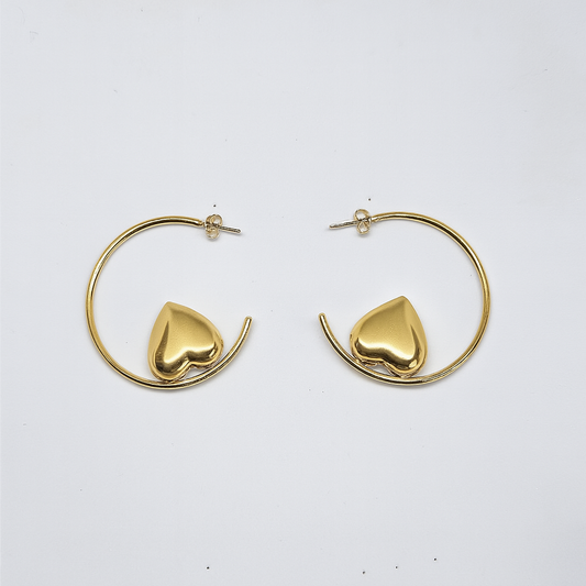 Gold hoop earrings with heart-shaped ends on a white background

