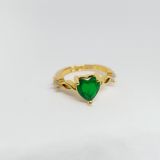 Gold ring with a green heart-shaped gemstone on a light gray background

