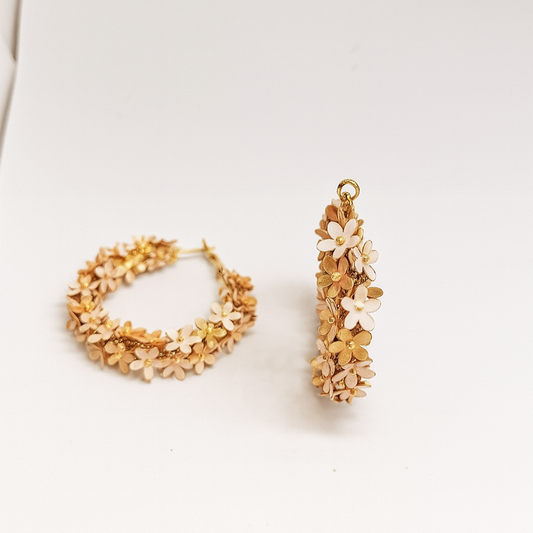 Pair of gold floral hoop earrings on a white surface

