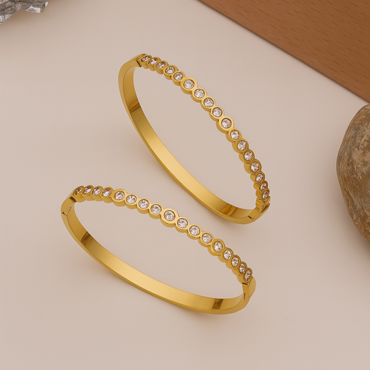 gold bangles with embedded stones on a neutral background


